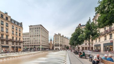 Fransa 'nın Lyon şehrindeki Place de la Republique' in hiperlapesi. Meydanda, tarihi binalarla çevrili büyük bir çeşme var ve insanlar banklarda oturuyor.