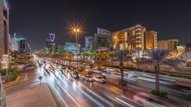 Riyad, Suudi Arabistan 'ın şehir havası gece zaman çizelgesi. Aydınlatılmış ünlü kuleler, gökdelenler, Kral Fahd Yolu ve yoğun trafik yer alıyor. Palmiyeler ve sokak lambaları şehrin içinden geçen ana otoyol boyunca uzanır.