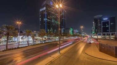 Suudi Arabistan, Riyad 'ın şehir manzarası gece zaman çizelgesi. Işıklı kulelerin, gökdelenlerin, King Fahd Yolu 'nun ve yoğun trafiğin panoramik görüntüsü. Palmiyeler ve sokak lambaları şehrin içinden geçen ana otoyolda.