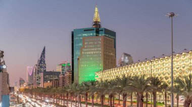 Suudi Arabistan, Riyad 'daki Kral Fahd Yolu' nun hava-gece zaman çizelgesi. Aydınlatılmış Riyad Ulusal Kütüphanesi yakınlarında modern kuleler ve gökdelenlerle çevrili araçlar ve taksilerle dolu.