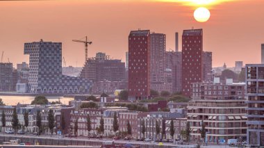 Hollanda, Rotterdam 'da gün batımında Katendrecht Yarımadası ve Maashaven Limanı' nın panoramik zaman çizelgesi. Şehir silueti, modern gökdelenler ve geleneksel Hollanda rıhtım evleri