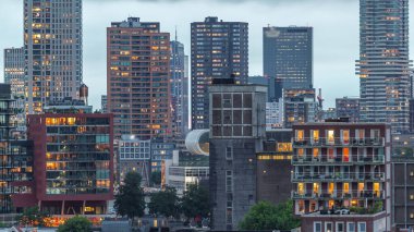 Rotterdam, Hollanda 'daki Katendrecht yarımadası ve Maashaven limanının hava ve gece geçiş zamanı. Günbatımından sonra parlayan pencereleri olan modern gökdelenler.