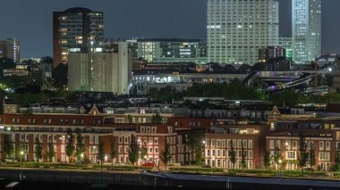 Geceleri Katendrecht yarımadasının panoramik zaman çizelgesi ve Hollanda Rotterdam 'daki Maashaven limanı. Aydınlatılmış şehir silüeti ve modern kuleleri olan geleneksel Hollanda rıhtım evleri