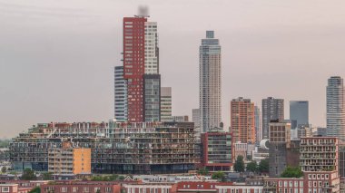 Rotterdam, Hollanda 'daki Katendrecht yarımadasının ve Maashaven limanının uçuş zamanı. Sabahları sıcak ışık, modern gökdelenler ve geleneksel Hollanda rıhtım evleri ile şehir silueti yükseliyor.