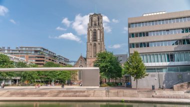 Laurenskerk 'in (Saint Lawrence Kilisesi) Grotekerkplein, Rotterdam' daki hiperlapesi. İnsanlar mavi bulutlu gökyüzünün altında çimlerde dinleniyorlar. Kanal merdivenlerinin yanında saati olan tarihi çan kulesi. Hollanda