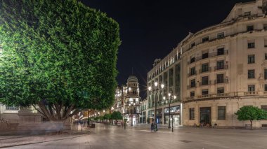 Avenida de la Constitucion gece vakti Seville, İspanya 'da aşırı hız. Iconic Adriatica binası akşam parlıyor. Modern sokak lambaları, yayalar ve şehir atmosferine sahip tarihi mimari