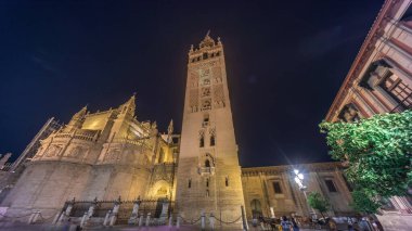 La Giralda ve Seville Katedrali geceleri aşırı hızlanarak altın ışıklarla parıldıyor. Tarihi çan kulesi, gotik detaylar ve aydınlatılmış sokaklar Sevilla, İspanya 'da büyülü bir atmosfer yaratıyor.