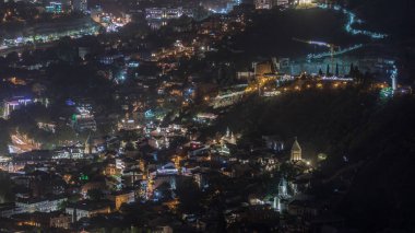 Georgia 'nın Tiflis şehrinde ahşap oymalı balkonları olan renkli geleneksel evler. Aydınlatılmış binalar, teleferik ve yol trafiği