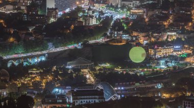 Rike Park 'ta gece vakti, yukarıdan. Tiflis 'in eski bir kasabasındaki modern şehir parkı. Şehirdeki dinlenme alanındaki ağaçlar ve çimenler. Aydınlatılmış Barış Köprüsü ve sıcak hava balonu. Georgia