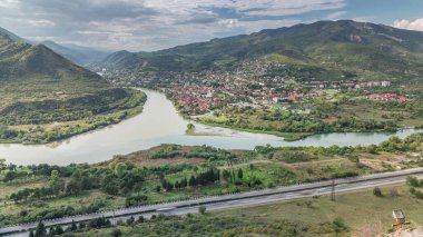 Kura ya da Mtkvari ve Aragvi nehirlerinin tek bir zaman diliminde birleşmesinin havadan görüntüsü. Gürcistan 'ın eski başkenti Mtskheta (sağda). Şehrin güzel manzarası, Georgia. Bulutlar geçip gidiyor