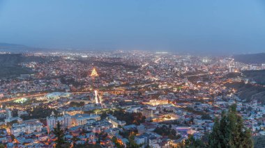 Alacakaranlıkta Tiflis şehri, Gürcistan 'dan gece geçiş zamanı. Şehir merkezinin ve Tiflis 'teki Kura Nehri' nin üst manzarası. Gün batımından sonra Gürcistan başkentinin havadan görünüşü