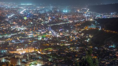 Rike Park 'ın olduğu şehir panoraması gece yukarıdan. Tiflis 'in eski bir kasabasındaki modern şehir parkı. Tarihi ve modern binalarla aydınlatılmış Barış Köprüsü ve hava balonu. Georgia