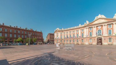 Capitole de Toulouse zaman çizelgesini gösteren panorama, Fransa 'nın Toulouse şehrinin tarihi belediye binası ve belediye kalbini, Capitole Meydanı' nda, çarpıcı mavi bulutlu gökyüzünün altında sergiliyor.