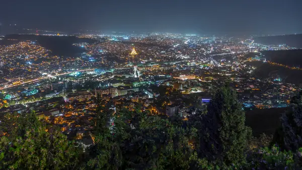 Tiflis şehir manzarası, Gürcistan günden geceye zaman. Şehir merkezinin ve Tiflis 'teki Kura Nehri' nin üst manzarası. Gökyüzünden Gürcistan başkentinin gökyüzü manzarası aydınlatılmış ünlü simgelerle