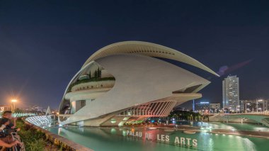 Panorama showing aerial timelapse of the Palau de les Arts Reina Sofia in Valencia before a fireworks show. Iconic opera house featuring futuristic curves and reflecting pools at night. Spain. clipart