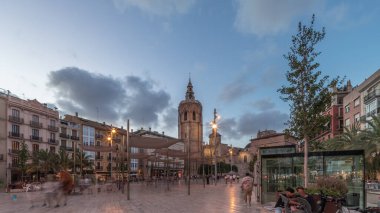 İspanya, Valencia 'daki Plaza de la Reina' da panoramik günden geceye geçiş süreleri aşırı hızlanıyor. Tarihi bir kilise kulesi, hareketli kafeleri ve akşam gökyüzünün altında merkezi bir çeşmesi olan canlı bir meydan..