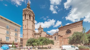 Valencia, İspanya 'da Plaza de la Reina' nın panoramik zaman atlaması. Tarihi bir kilise kulesi, hareketli kafeler ve sıcak Akdeniz mavi bulutlu gökyüzünün altında merkezi bir çeşme ile dolu canlı bir meydan..