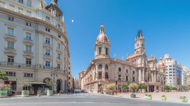 Panorama, Plaza de Ayuntamiento 'da Valencia Belediye Binası' nı (Ajuntament de Valencia) gösteriyor. Mavi gökyüzünün altında saat kulesi olan tarihi bir bina. İspanya 'nın ana meydanında gezinen insanlar