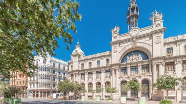 Belediye Binası Meydanı 'nda (Plaza del Ayuntamiento Meydanı) tarihi Posta Ofisi' ni (Palau de les Comunicacions) gösteren panorama. Süslü cephe, trafik ve İspanya şehir merkezinde mavi bir gökyüzü..