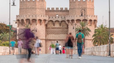 Serrans Towers (Torres de Serranos) timelapse in Valencia, Spain. A grand medieval gate from the city's ancient walls. People walking on a bridge at evening before sunset near historic landmark clipart