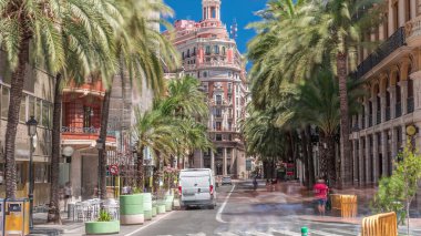 Valencia Bankası 'nın tarihi tarihi merkezi Valencia, İspanya' da. Göz kamaştırıcı bir mimari, palmiye kaplı bir sokak ve parlak mavi gökyüzü altında yoğun bir trafik. Şehir finans bölgesi sahnesi