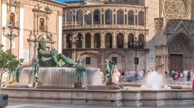 Valencia, İspanya 'daki ikonik Turia Pınarı ile birlikte Plaza de la Virgen' den Timelapse. Neptün heykeli Turia Nehri ve kanallarını temsil eder. Meydanda yürüyen gölgelerle gezen insanlar