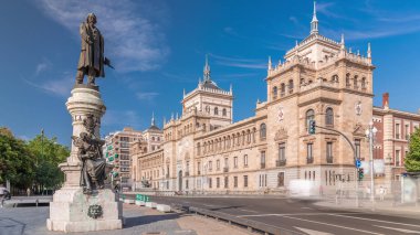 İspanya, Valladolid Plaza de Zorrilla 'daki Süvari Akademisi' nden Timelapse. Karmaşık mimarisi olan tarihi askeri bina mavi gökyüzünün altında ve bulutların arasından geçen yoğun bir şehir manzarası ile çevrili..