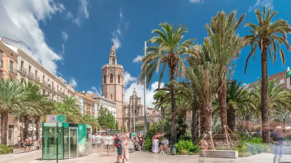 Valencia, İspanya 'da Plaza de la Reina' nın panoramik zaman atlaması. Tarihi bir kilise kulesi, hareketli kafeler ve sıcak Akdeniz semaları altında palmiyeleri olan merkezi bir çeşme..