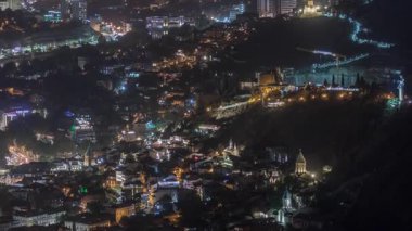 Georgia 'nın Tiflis şehrinde ahşap oymalı balkonları olan renkli geleneksel evler. Aydınlatılmış binalar, teleferik ve yol trafiği