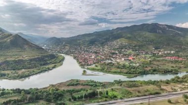 Kura ya da Mtkvari ve Aragvi nehirlerinin tek bir zaman diliminde birleşmesinin havadan görüntüsü. Gürcistan 'ın eski başkenti - Mtskheta doğru. Şehrin güzel manzarası, Georgia. Bulutlar geçip gidiyor