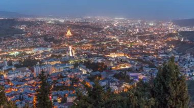 Alacakaranlıkta Tiflis şehri, Gürcistan 'dan gece geçiş zamanı. Şehir merkezinin ve Tiflis 'teki Kura Nehri' nin üst manzarası. Gün batımından sonra Gürcistan başkentinin havadan görünüşü