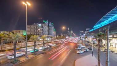 Riyad, Suudi Arabistan 'ın şehirsel gece zaman çizelgesinde aydınlık kuleler, gökdelenler, Kral Fahd Yolu ve yoğun trafik yer alıyor. Palmiyeler ve sokak lambaları alışveriş merkezinin yakınındaki ana otoyolda.