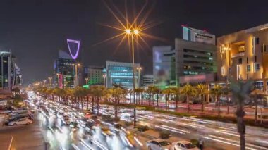 Riyad, Suudi Arabistan 'ın şehir havası gece zaman çizelgesi. Aydınlatılmış ünlü kuleler, gökdelenler, Kral Fahd Yolu ve yoğun trafik yer alıyor. Palmiyeler ve sokak lambaları şehrin içinden geçen ana otoyol boyunca uzanır.