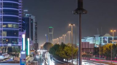 Suudi Arabistan 'ın Riyad kentindeki ikonik bükümlü gökdeleniyle King Fahd Yolu' ndaki yoğun karayolu trafiğinin hava takvimi görüntüsü. Dünyanın en yüksek sekizinci büküm kulesi. Aydınlatılmış sokaklar ve ağaçlar