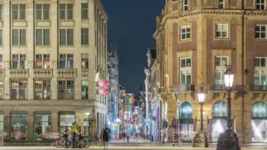 Amsterdam 'daki Baraj Meydanı' nda gece zaman dilimi, Hollanda. Şehrin tarihi merkezidir ve müzeler, dükkanlar ve oteller içerir. Aydınlatılmış Kalverstraat Caddesi