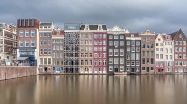 Damrak 'taki renkli Kanal Evleri' nin gece ışığında aşırı hızlanması dramatik bulutların altında geçen teknelerle suya yansıdı. Hollanda, Amsterdam 'ın büyüleyici manzarası