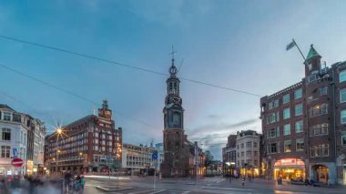 Munttoren Kulesi ve çiçek pazarı. Amsterdam şehir merkezinin panoramik günden geceye geçiş dönemi aşırı hızlanması tramvaylı sokak trafiği. Gün batımından sonra şehir manzarası. Hollanda