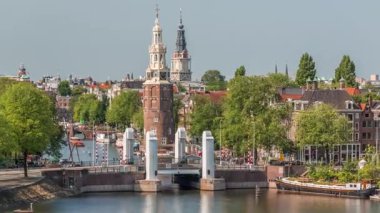 Amsterdam şehri, Montelbaanstoren Kulesi 'nin yer aldığı, kanal boyunca uzanan şehir manzaralı bir zaman çizelgesi. Eski kentteki tarihi Hollanda evleri, köprüler, mavnalar ve yüzen evler