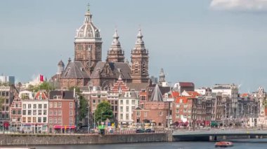 Merkez İstasyonu yakınlarındaki Amsterdam Eski Merkezi 'nde Aziz Nicholas Bazilikası ile birlikte havadan şehir manzarası. Tekne istasyonunda sahil şeridi boyunca yürüyen insanlar var. Amsterdam, Hollanda