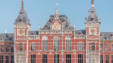 Amsterdam Merkez Tren İstasyonu 'nun zaman çizelgesi yaz günü mavi gökyüzünde bulutlarla kapanıyor. Amsterdam, Hollanda