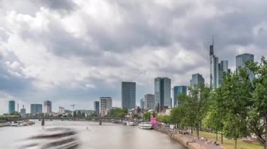 Almanya 'nın Frankfurt kentindeki ana nehir üzerindeki tarihi Eiserner Steg Demir Köprüsü' nün hızlandırılması. Gökdelenler ufuk çizgisi ve kıyı şeridi bulutlarla dolu bir gökyüzünün altında yansıyor.