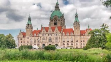 Hanover 's New Town Hall' un hiperlapse 'si, bulutlu bir gökyüzünün altında park ve göl ile çevrili tarihi bir kale gibi bir yapı. Su ve yeşillik üzerindeki yansımalar bu ikonik şehir manzarası zaman çizelgesini oluşturuyor. Almanya
