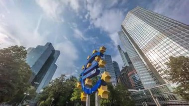 Avrupa Merkez Bankası 'nın eski genel merkezi yakınlarındaki Frankfurt şehir merkezinde Avrupa para birimi tabelasının zaman aşımına uğraması. Güneş ışığı bulutlu bir gökyüzünde gökdelenlerden yansıyor. Almanya