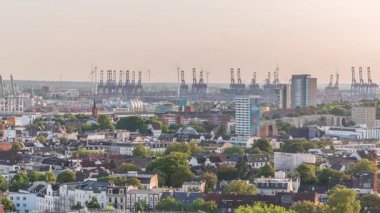 Stadyum, modern ofis ve konut binaları ile Hamburg 'un gökyüzü çizgisi zaman çizgisi, sıcak akşam ışığı, arka planda kargo limanında vinçler ve Almanya' nın sığınak çatısından kentsel panorama