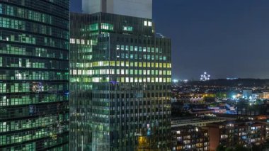 Brüksel 'deki cam cepheli ve parlayan pencereli modern gökdelenlerin ve kulelerin hava gece zaman çizelgesi. Arka planda Eglise Notre-Dame de Laeken 'in yer aldığı aydınlanmış şehir silueti. Belçika