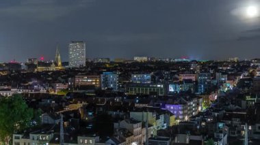 Brüksel üzerinde, Schaerbeek 'teki tren istasyonuna yakın gökdelende hava gecesi panoraması. Yerleşim yerleri, aydınlatılmış Saint-Servais Kilisesi Belçika 'nın başkentindeki kırmızı çatılarla çevrili.