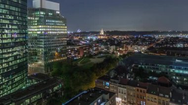 Brüksel kentsel manzarasının, ofis gökdelenleriyle konut alanlarını harmanlayan gece uçuşu. Yeşil park çimenleri, tarihi çatılar ve modern mimari Belçika 'da çeşitli bir şehir manzarası oluşturur