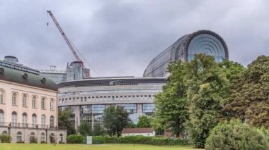 Brüksel 'deki Avrupa Mahallesi' ndeki binalar Avrupa Parlamentosu, Komisyon ve dramatik bulutlu gökyüzü altındaki kurumlarla aynı tarihe denk geliyor. Leopold Park ön planda yeşil çimenler ve ağaçlarla