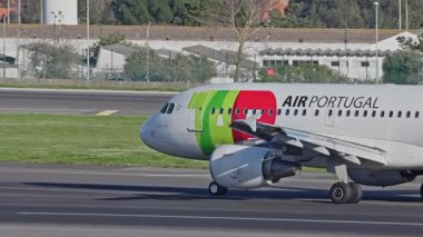 Lizbon, Portekiz - 25 Şubat 2025: Lizbon Havaalanı 'na indikten sonra terminallere giden ticari uçak. TAP Air Portugal Havayolları şehrin silueti ve havaalanı altyapısı ile taksilerde ilerliyor