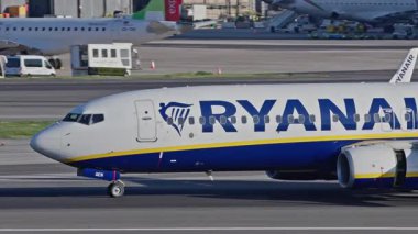Lizbon, Portekiz - 25 Şubat 2025: Lizbon Havaalanı 'na indikten sonra terminallere giden ticari uçak. Ryanair Havayolları şehir silueti ve havaalanı altyapısı ile taksilerde ilerliyor.